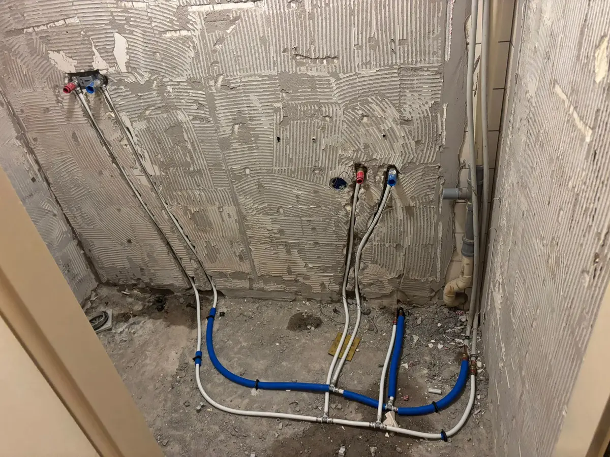 Nieuwe water- en cv-leidingen aangelegd op de muur tijdens een badkamerrenovatie.