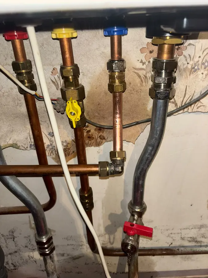 Koperen leidingen met afsluiters en gasleiding onder een cv-ketel