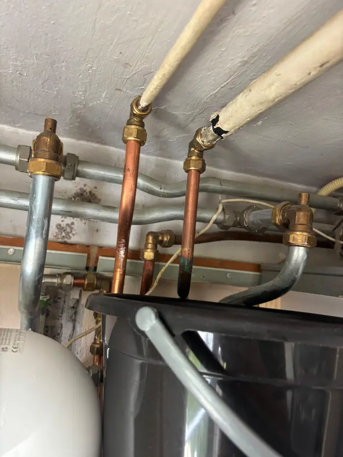 Koperen leidingen met afsluiters boven een boilerinstallatie